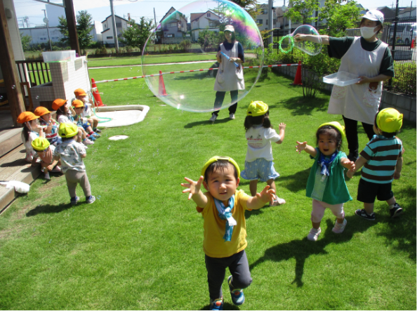 園庭でシャボン玉遊びをする園児たち